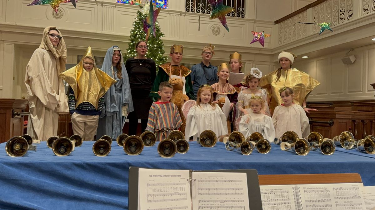 Handbells set out on a table in front of the Christmas pageant cast